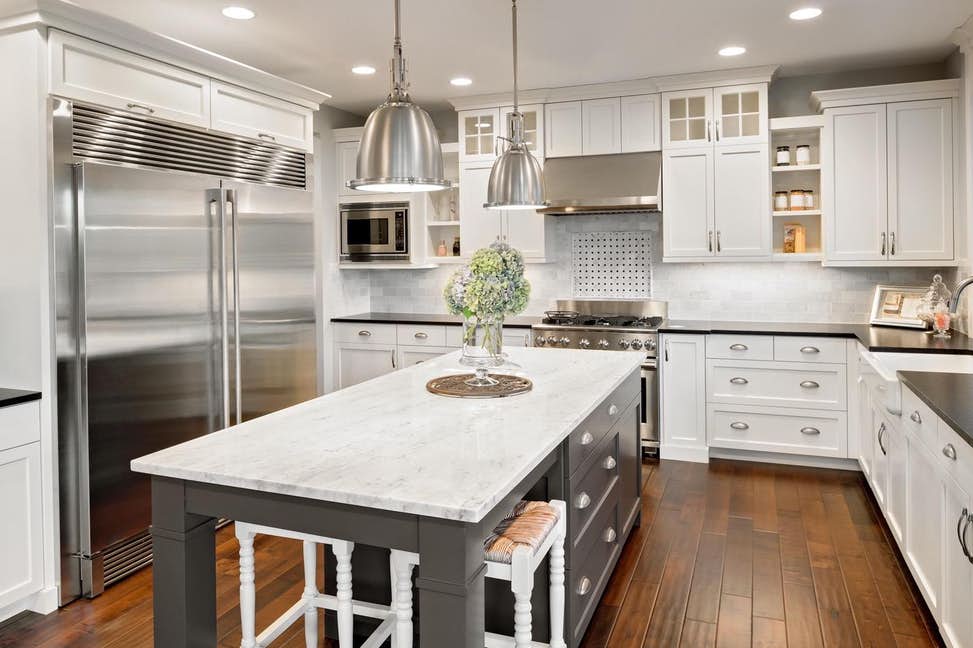 Bright fitted kitchen with island and white cabinetry